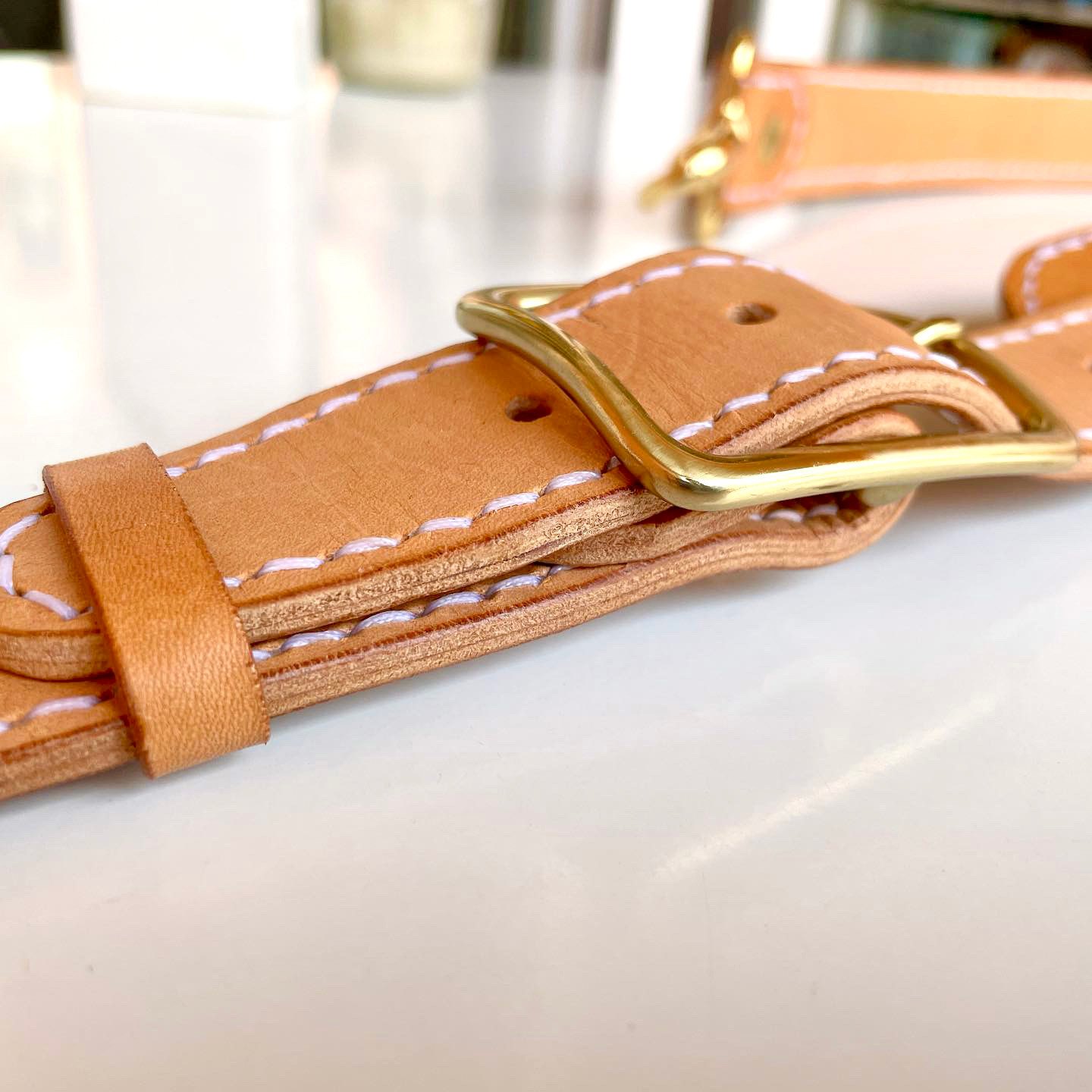 The brass buckle and keeper on the shoulder strap of the Munich Bag by 1985 Studio, the vegetable-tanned leather stitched along both edges