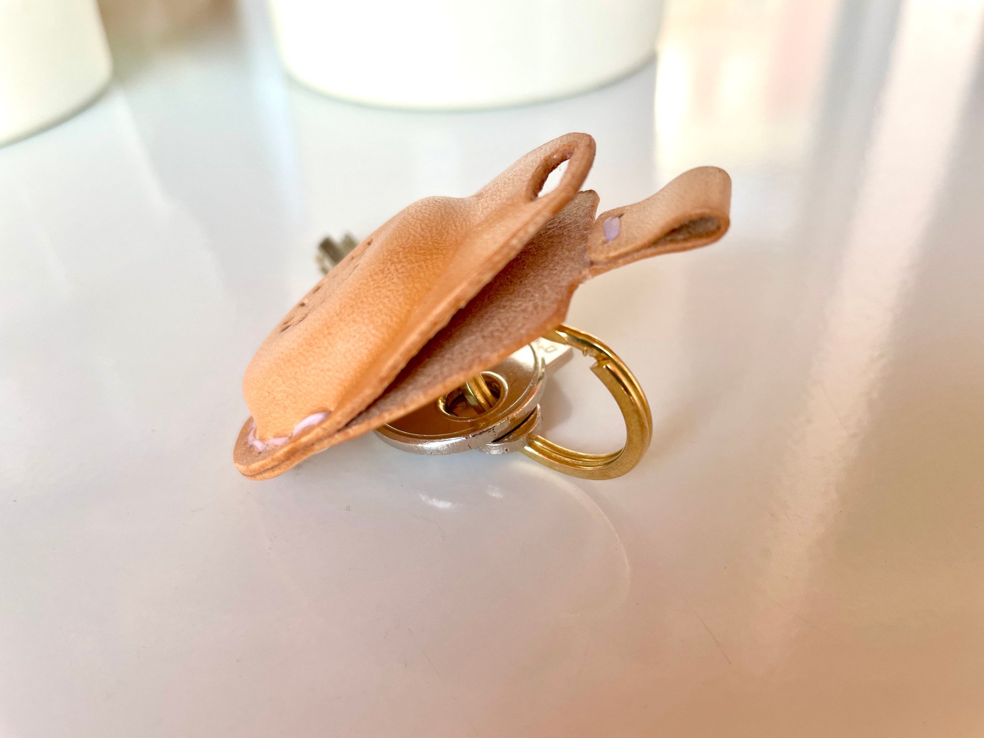 AirTag key fob by 1985 Studio opened, its domed front of vegetable-tanned leather lifted from the back, the brass ring and keys underneath