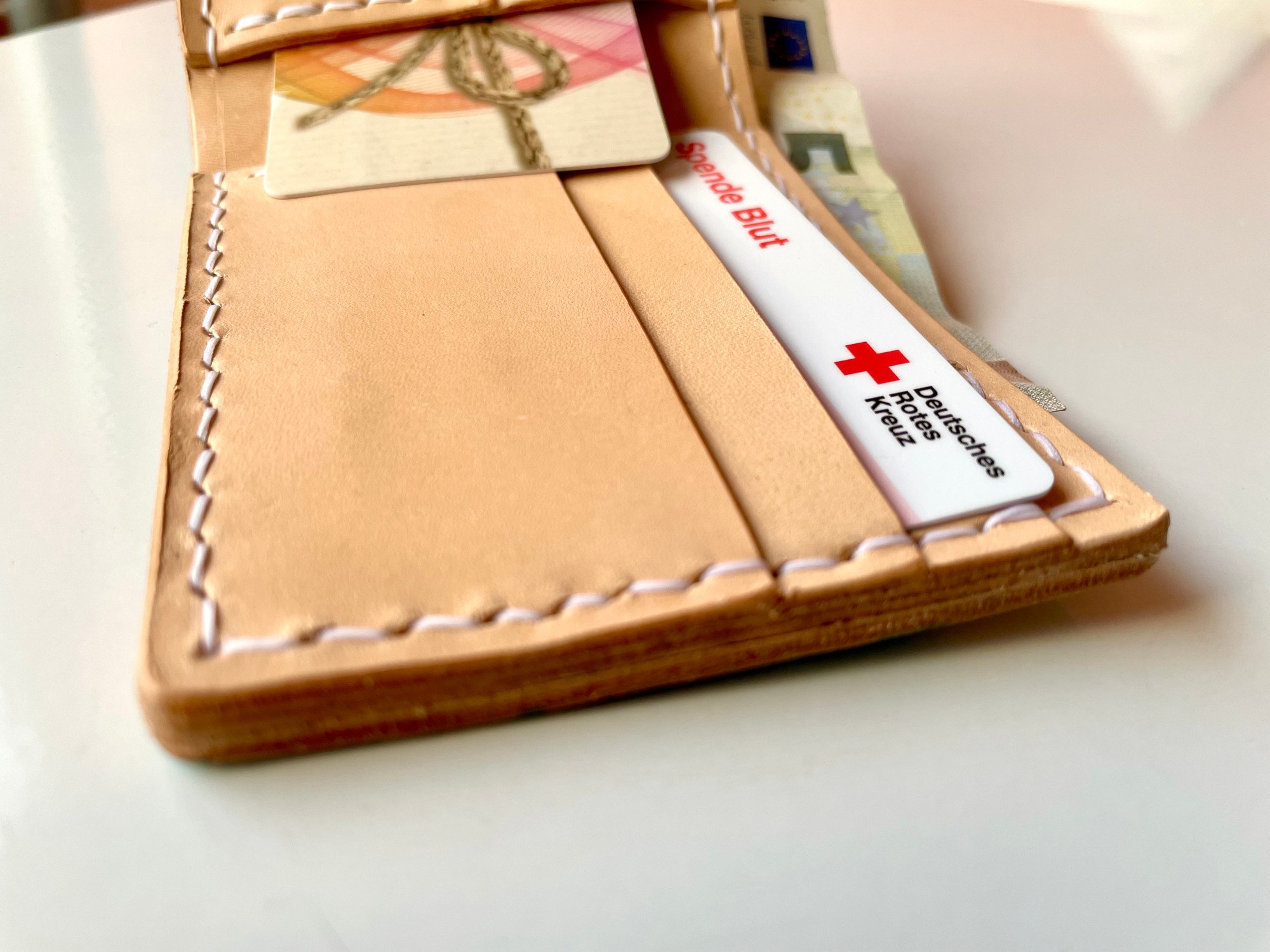 The card slots of the Wave Wallet by 1985 Studio up close, cards tucked in and the vegetable-tanned leather stitched in white
